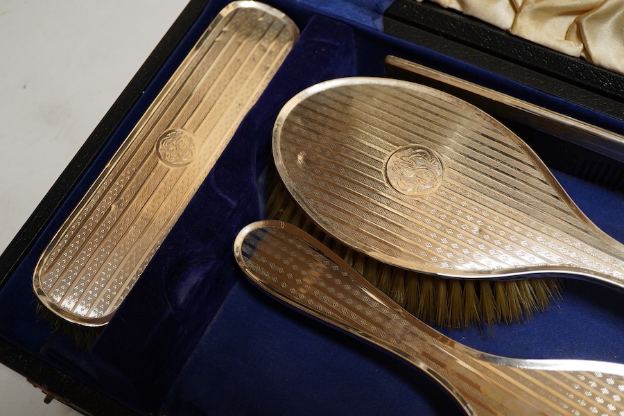 A George V silver six piece engine turned dressing table set Birmingham, 1922 Carringon & Co, comprising hand mirror, pair hairbrushes, pair clothes brushes and a mounted tortoiseshell comb, initialled, in a fitted case